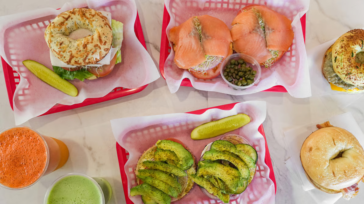 A spread of bagel sandwiches, lox, and avocado bagels with fresh juice